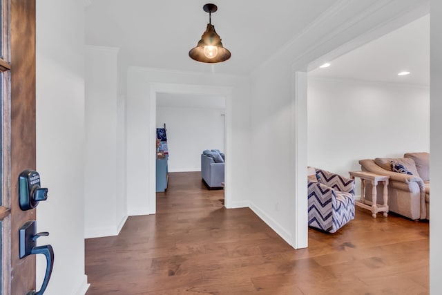 corridor with ornamental molding, baseboards, and wood finished floors