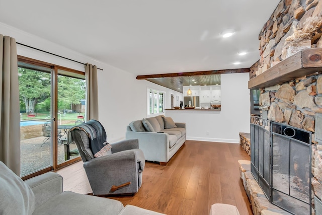 living room with a fireplace, plenty of natural light, wood finished floors, and baseboards