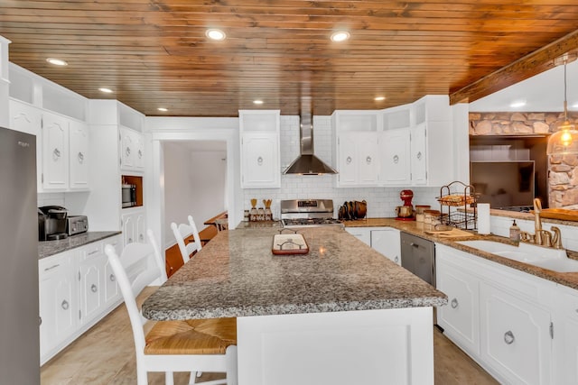 kitchen featuring a breakfast bar, backsplash, appliances with stainless steel finishes, a sink, and wall chimney exhaust hood