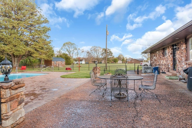 view of patio / terrace featuring a shed, fence, a fenced in pool, and an outbuilding