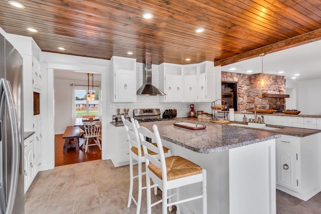 kitchen with wooden ceiling, appliances with stainless steel finishes, a sink, wall chimney range hood, and backsplash