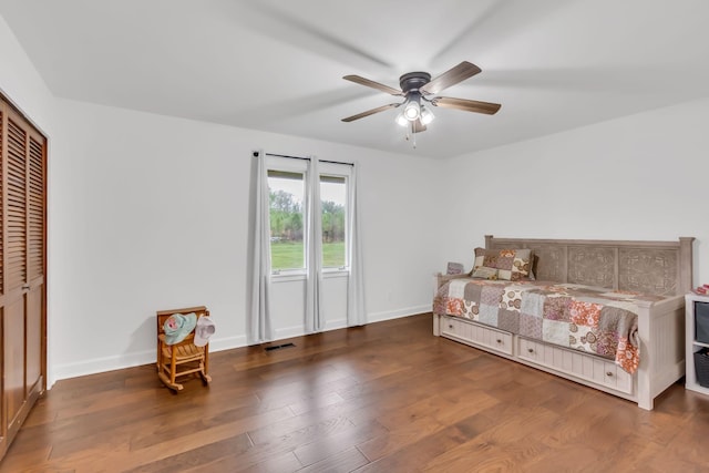 bedroom with visible vents, baseboards, a ceiling fan, wood finished floors, and a closet