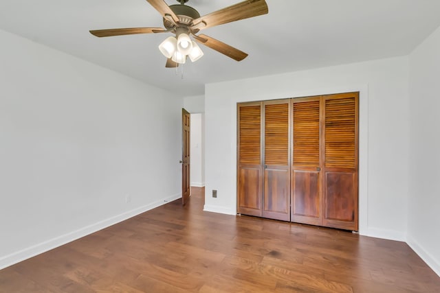 unfurnished bedroom featuring a ceiling fan, a closet, baseboards, and wood finished floors