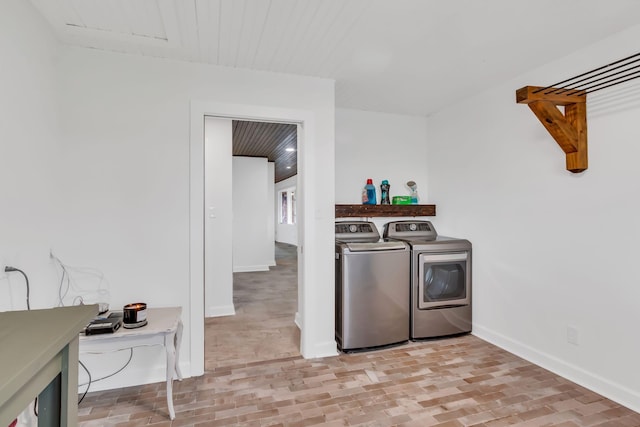 washroom featuring brick floor, wooden ceiling, separate washer and dryer, laundry area, and baseboards