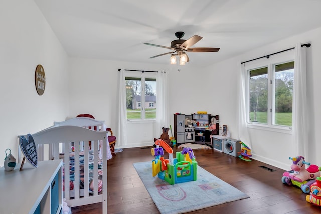 bedroom featuring a nursery area, multiple windows, wood-type flooring, and visible vents