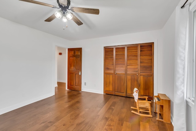 unfurnished bedroom featuring a ceiling fan, a closet, baseboards, and wood finished floors