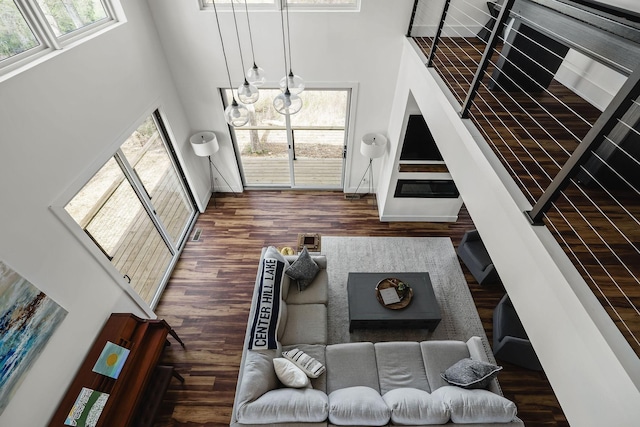 living area featuring plenty of natural light, wood finished floors, and a towering ceiling