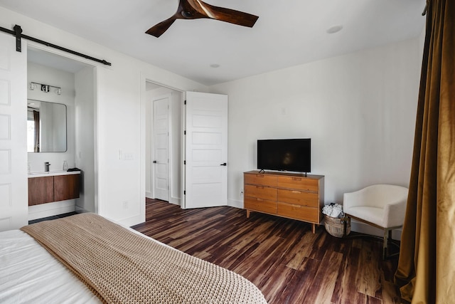 bedroom with a barn door, wood finished floors, a ceiling fan, and baseboards