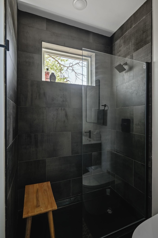 full bathroom with a tile shower and toilet