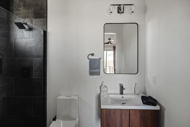 bathroom with tiled shower, vanity, and toilet