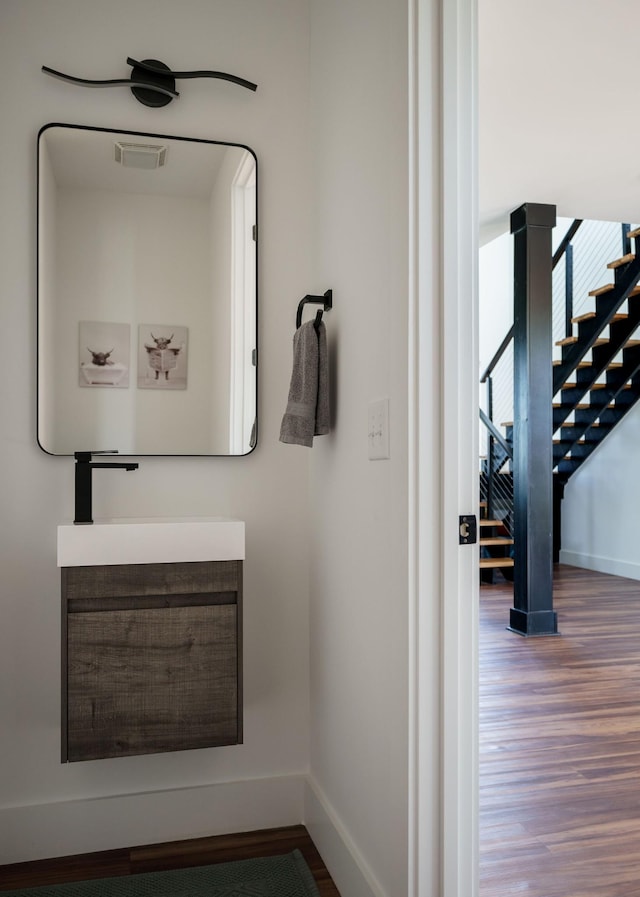 bathroom with visible vents, a sink, baseboards, and wood finished floors