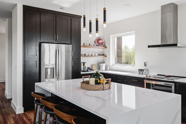 kitchen with decorative light fixtures, dark wood finished floors, open shelves, appliances with stainless steel finishes, and wall chimney exhaust hood