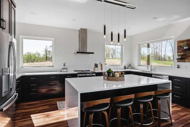 kitchen featuring a breakfast bar, a kitchen island, wall chimney range hood, stainless steel fridge with ice dispenser, and dark wood-style floors