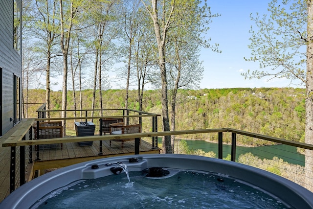 deck with a hot tub and a wooded view