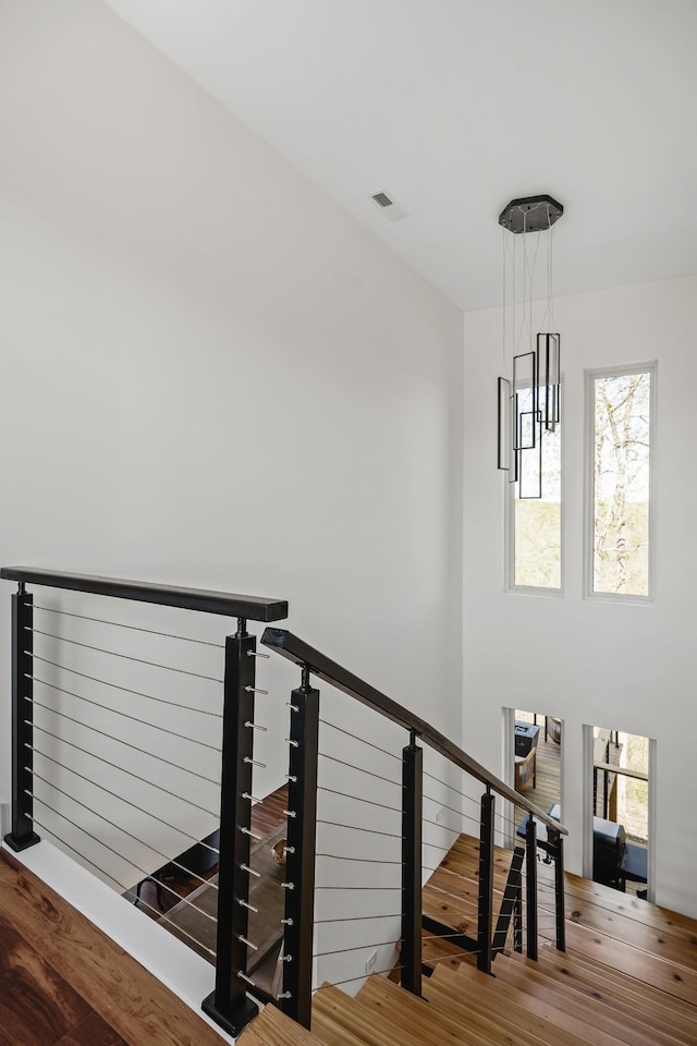 staircase featuring wood finished floors, visible vents, and an inviting chandelier