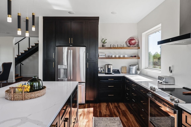 kitchen featuring dark wood-style floors, appliances with stainless steel finishes, light stone countertops, wall chimney range hood, and open shelves