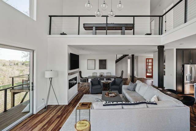 living area with dark wood-type flooring, a wealth of natural light, and baseboards