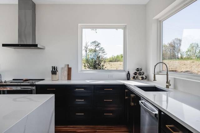 kitchen with wall chimney exhaust hood, dark cabinets, and stainless steel appliances