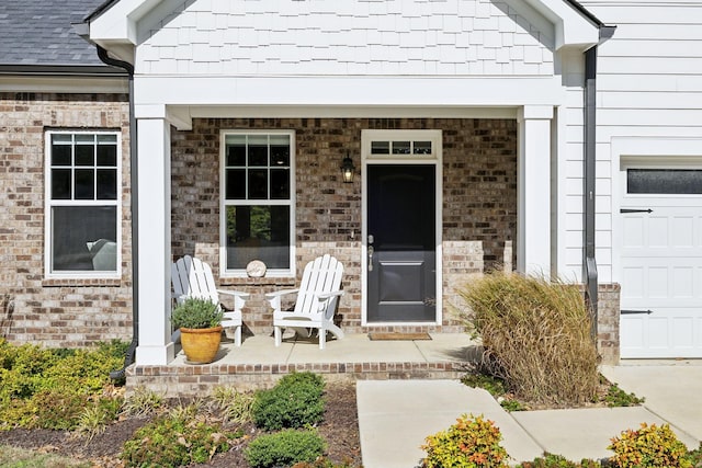 doorway to property with a shingled roof, brick siding, and a garage