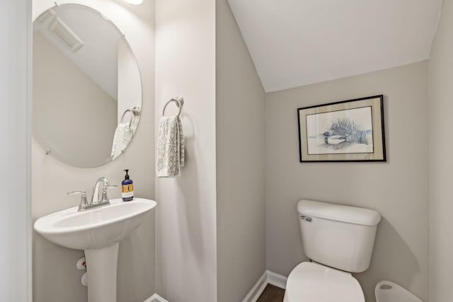 half bath featuring toilet, baseboards, and lofted ceiling