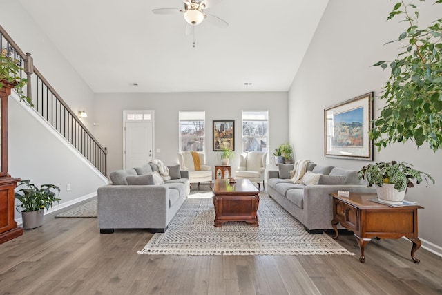 living room featuring visible vents, ceiling fan, wood finished floors, baseboards, and stairs