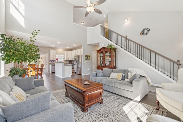 living room with dark wood-style floors, high vaulted ceiling, stairway, and ceiling fan