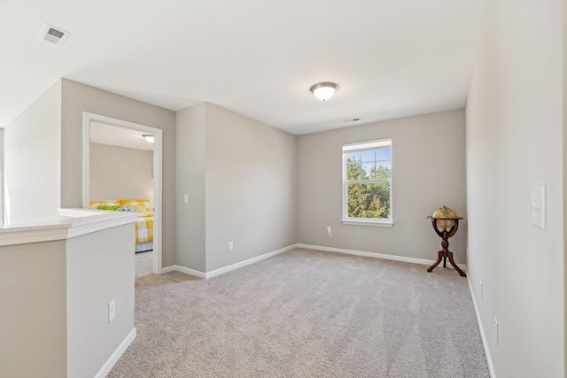 spare room featuring light carpet, visible vents, and baseboards