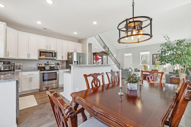 dining room with stairway, recessed lighting, light wood-style flooring, and an inviting chandelier