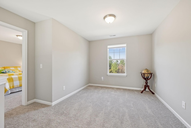 carpeted spare room featuring visible vents and baseboards