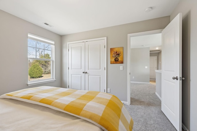 bedroom featuring a closet, light carpet, visible vents, and baseboards