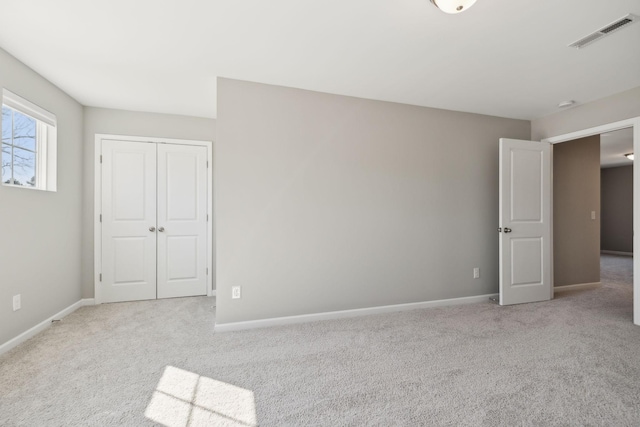 unfurnished bedroom with carpet, a closet, visible vents, and baseboards