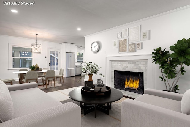 living area featuring recessed lighting, dark wood-style flooring, a fireplace, and crown molding