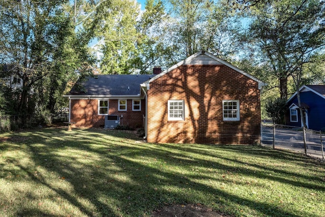 view of side of property with a yard, a chimney, fence, and brick siding