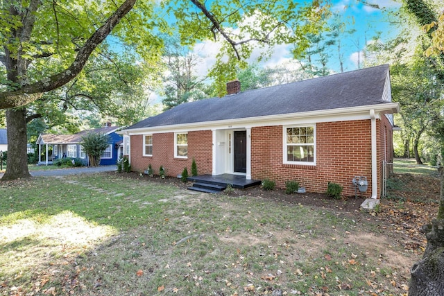 single story home with a front yard, roof with shingles, a chimney, and brick siding