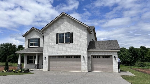 view of front of home featuring roof with shingles, brick siding, and driveway