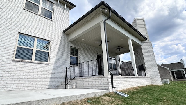 exterior space featuring ceiling fan, a lawn, and brick siding