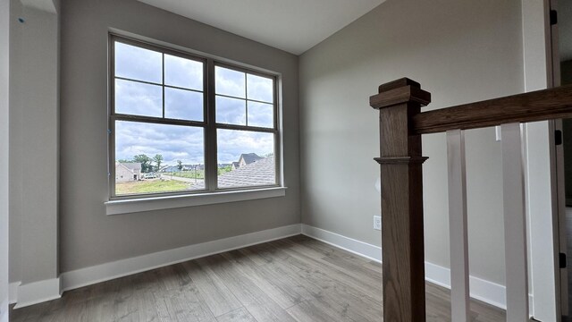 interior space featuring baseboards, vaulted ceiling, and wood finished floors