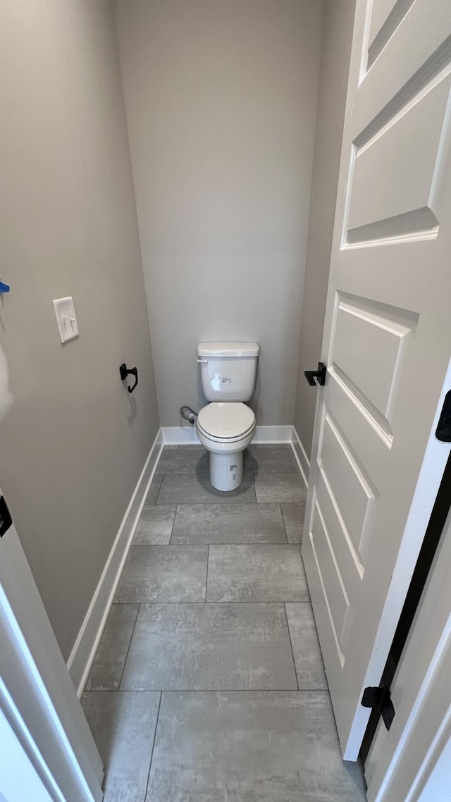 bathroom featuring toilet, baseboards, and wood finish floors