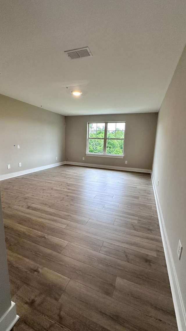 unfurnished room featuring visible vents, baseboards, and wood finished floors