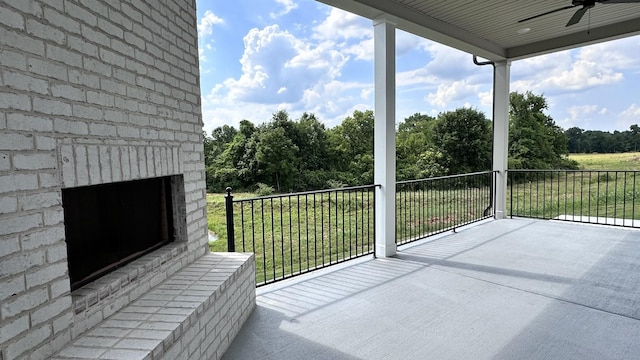 balcony featuring ceiling fan and an outdoor brick fireplace