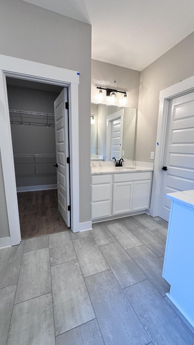 bathroom featuring a spacious closet, vanity, and baseboards