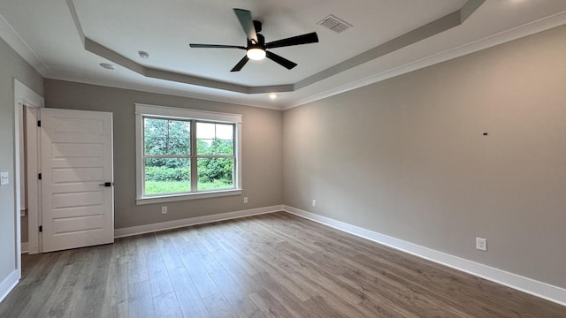 unfurnished room featuring wood finished floors, a ceiling fan, visible vents, baseboards, and a tray ceiling