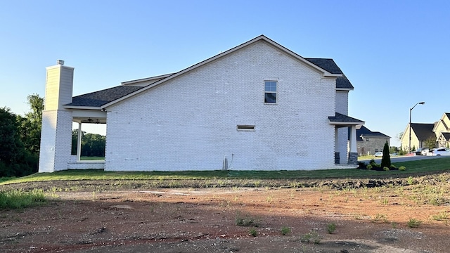 view of side of home with brick siding and a chimney