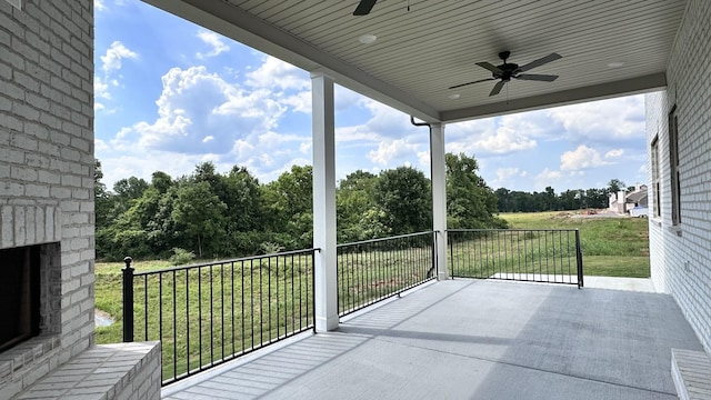 balcony featuring ceiling fan and an outdoor brick fireplace