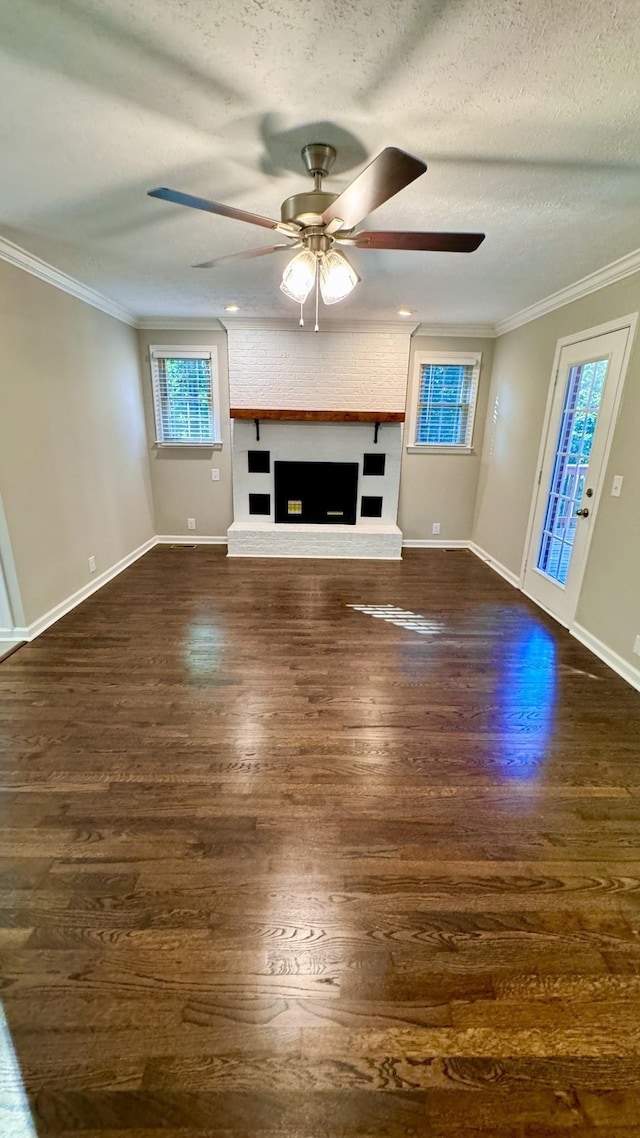 unfurnished living room featuring dark wood-type flooring, a brick fireplace, crown molding, and a textured ceiling