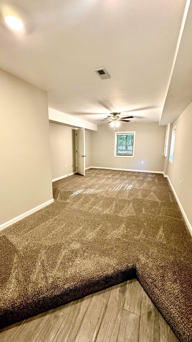 carpeted spare room with a ceiling fan, visible vents, and baseboards