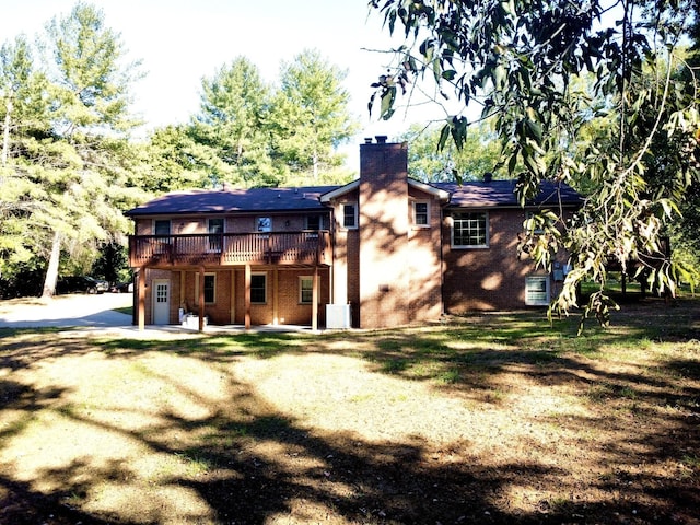 back of house featuring a patio area, a chimney, a deck, and brick siding