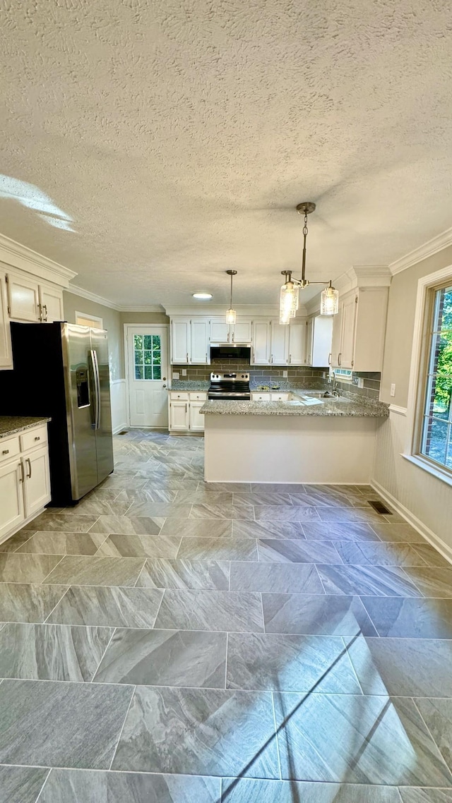 kitchen featuring a wainscoted wall, white cabinetry, appliances with stainless steel finishes, backsplash, and crown molding