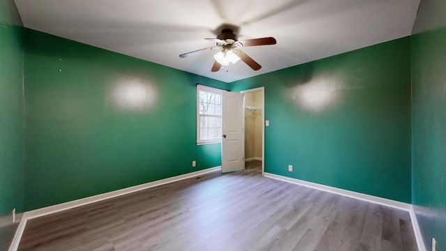 empty room with ceiling fan, wood finished floors, and baseboards