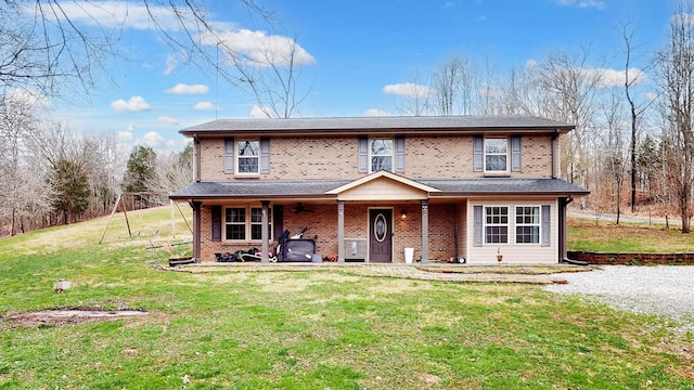 traditional home with a front yard, covered porch, and brick siding